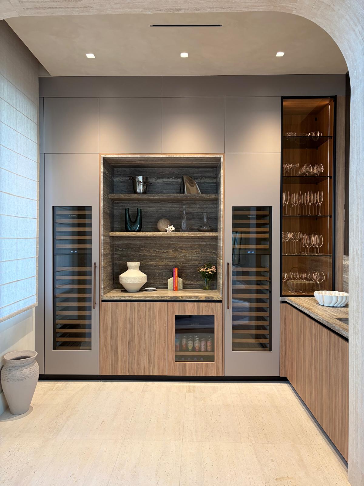 Built-in bar with wine fridges, glass display cabinets, and backlit shelving