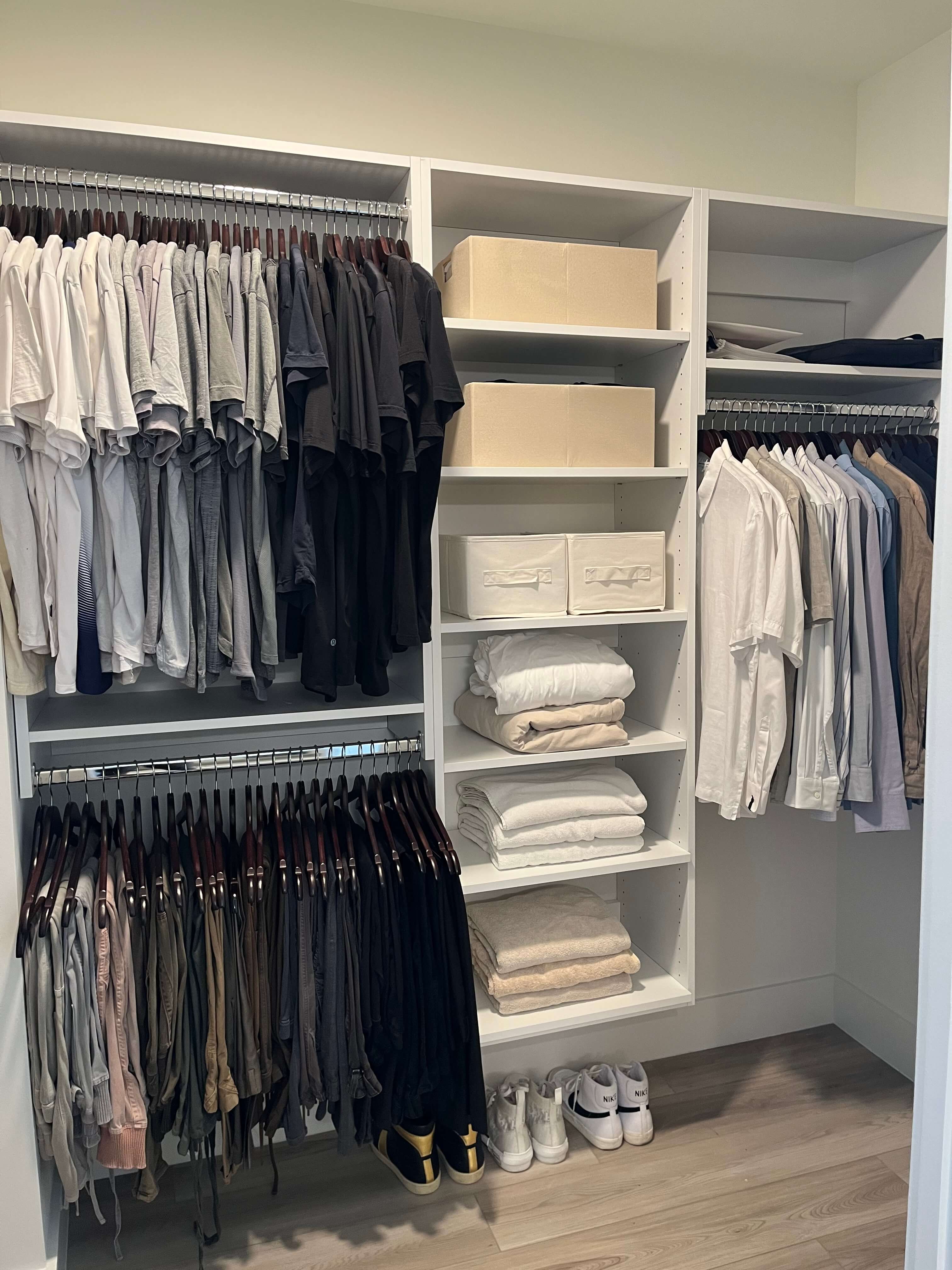 Walk-in closet with clothing sorted by color, storage boxes, folded towels, and neatly arranged shoes