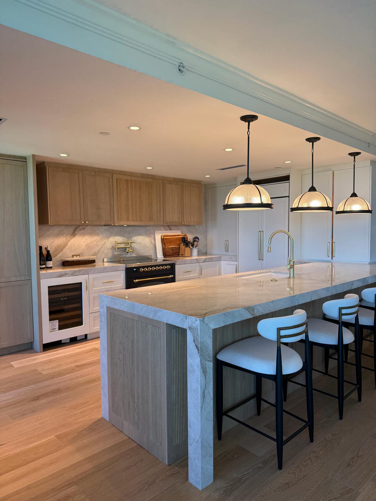 Kitchen with marble waterfall island, bar seating, and organized pantry shelving