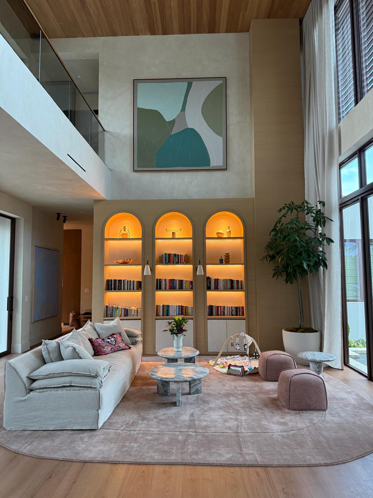 Double-height living room with arched, backlit built-in shelving