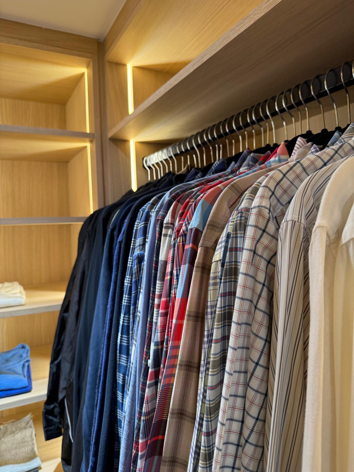 Walk-in closet shelf over organized clothing racks